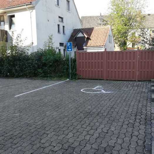 Behindertenparkplatz mit Markierung auf dem Parkplatz und dem zugehörigen Hinweisschild